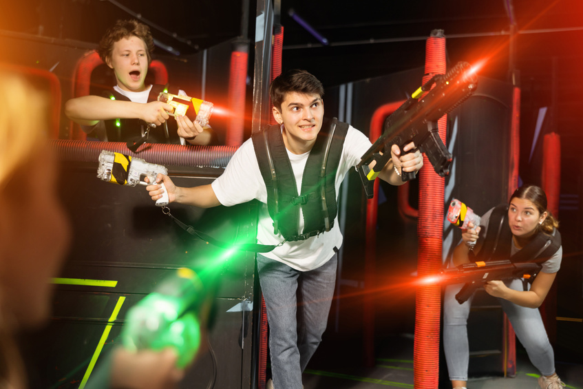 Three people having fun playing lasertag in arena